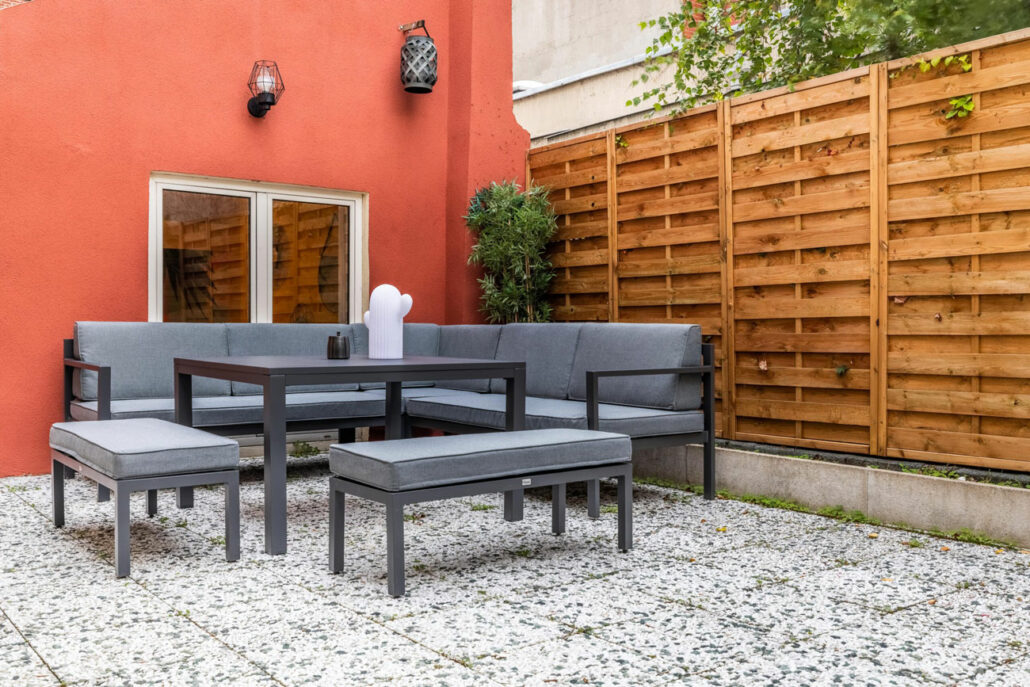 Canapé gris d'extérieur avec une table à manger sur une terrasse.