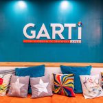 Le logo de l'école de graphisme Garti se trouve sur un mur bleu dans une salle détente.